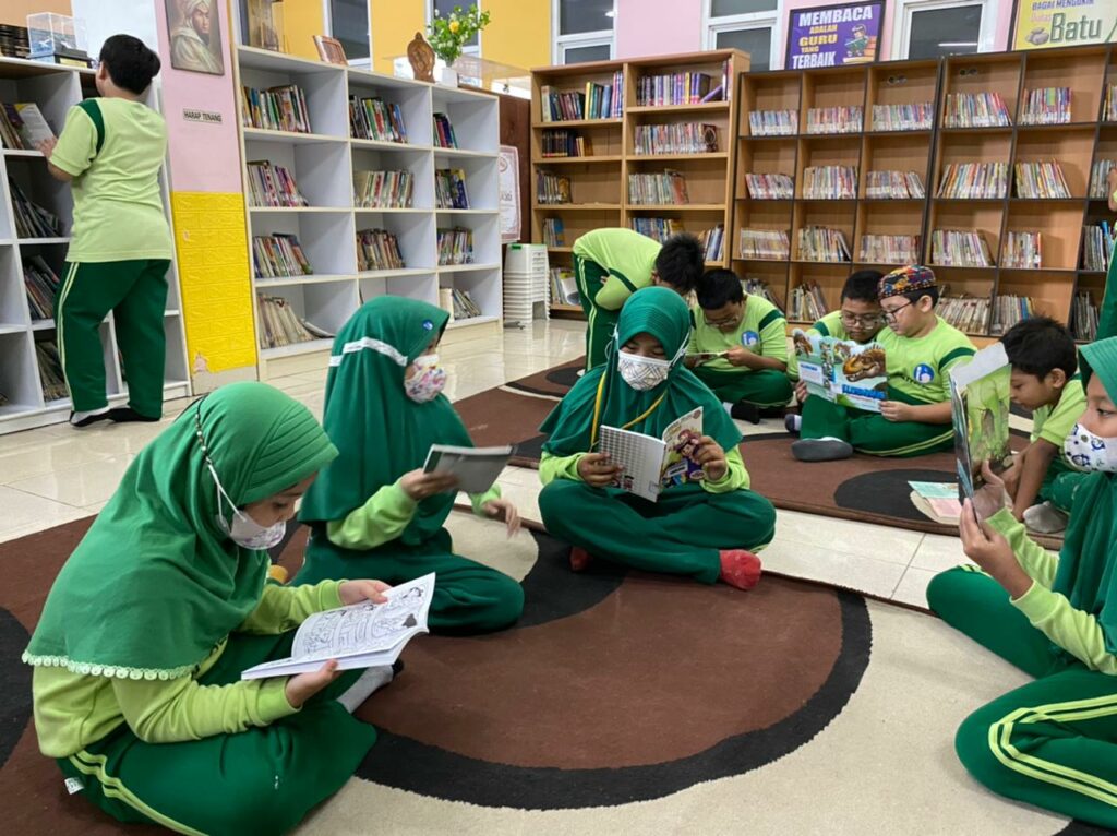 Murid SDIA 12 sedang membaca buku di perpustakaan.