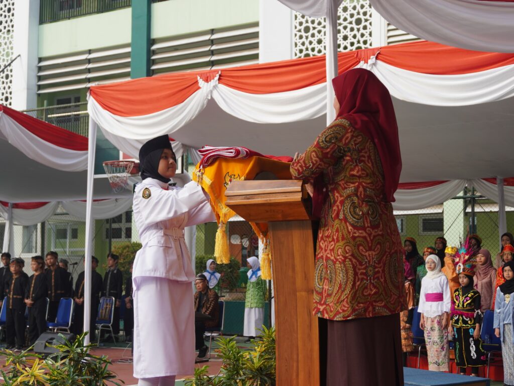 Anggota Paskibra dari murid SD Islam Al Azhar 12 Cikarang sedang mengibarkan bendera Merah Putih pada upacara peringatan kemerdekaan.