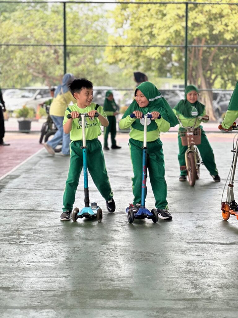 Murid mengikuti kegiatan scooter dan bersepeda di area sekolah untuk melatih keseimbangan, koordinasi gerak, serta keberanian dengan tetap memperhatikan keselamatan.